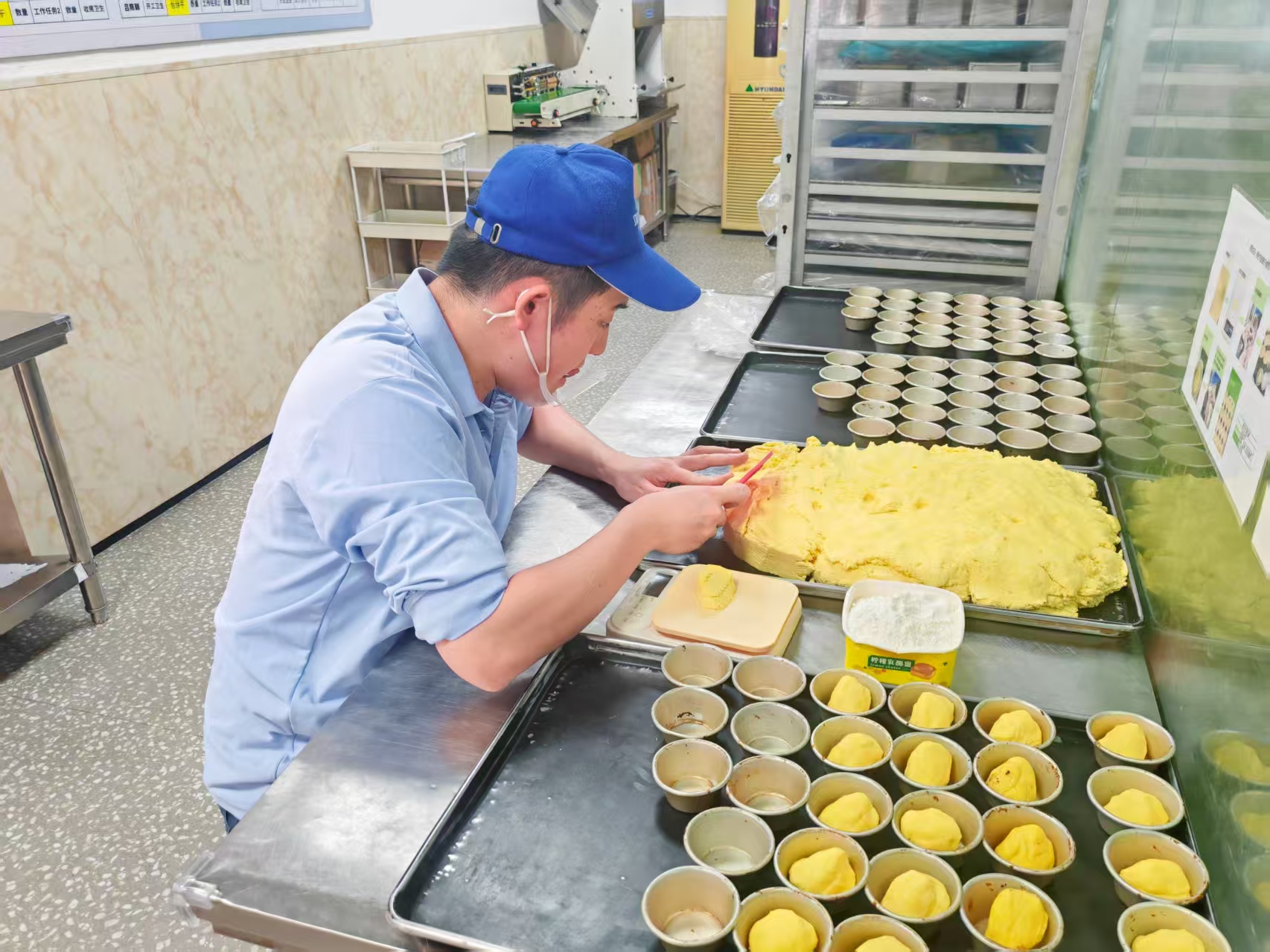 孤独症员工戴着口罩,用干净的双手正在认真制作蛋挞皮。人民网记者 王子锋摄