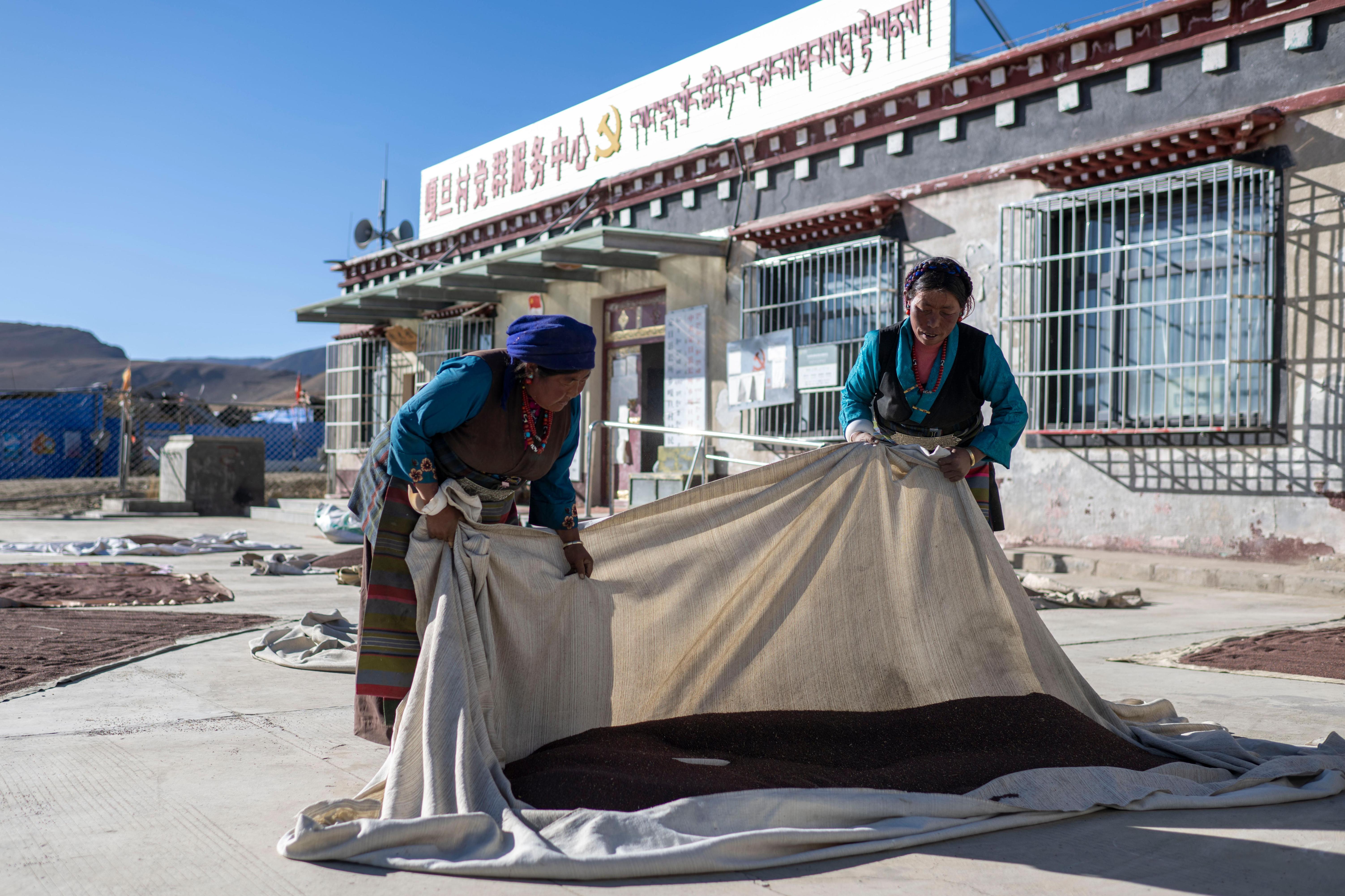 在嘎旦村党群服务中心，村民正在晒菜籽。人民网记者 翁奇羽摄