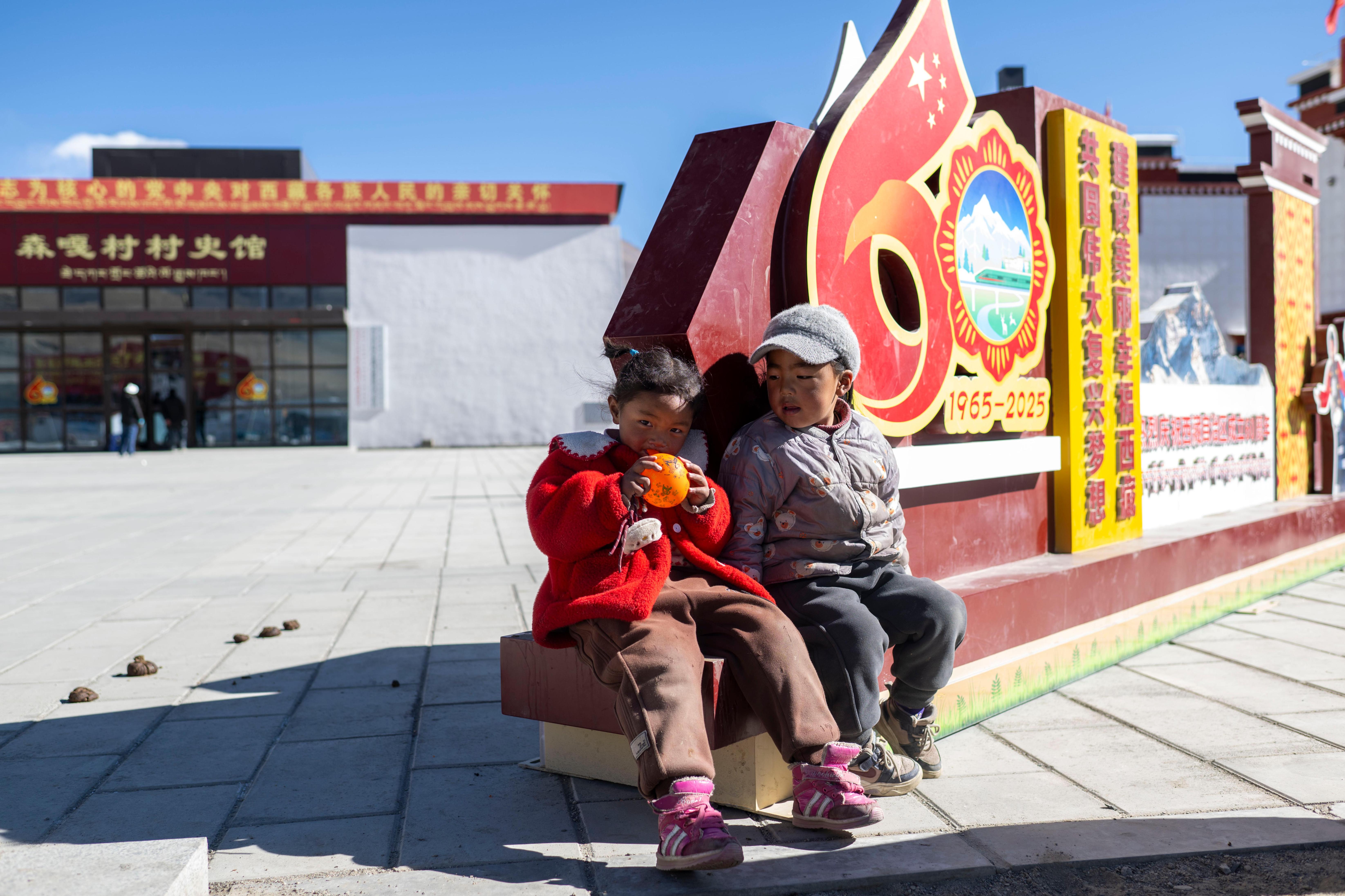 2025年12月11日,在西藏定日县长所乡森嘎村,小朋友们在村史馆前的广场上玩耍。人民网记者 翁奇羽摄