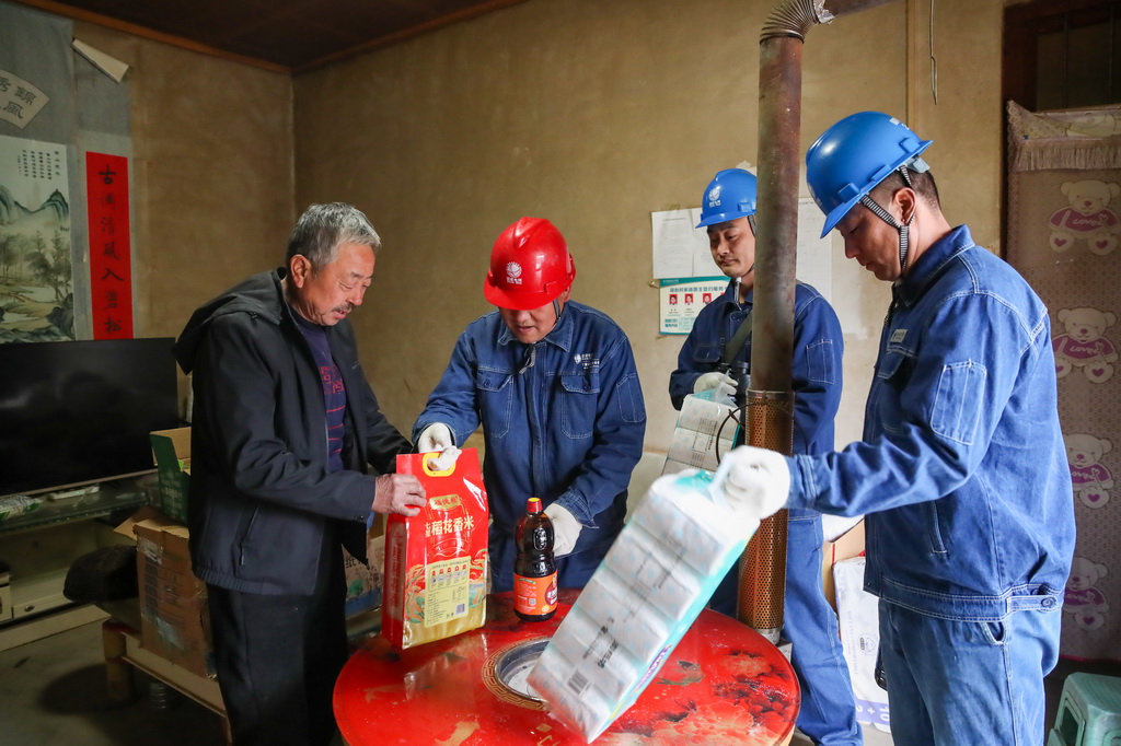 1月18日，在甘肃省陇南市两当县泰山乡同心村，杨店供电所职工将代购的生活物资交给村民曹永礼。