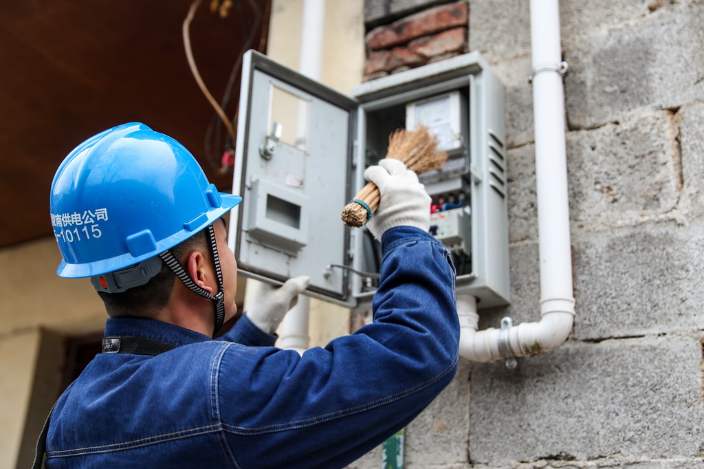 1月18日，在甘肃省陇南市两当县泰山乡同心村，杨店供电所职工王超在一户村民家清扫配电箱蛛网。