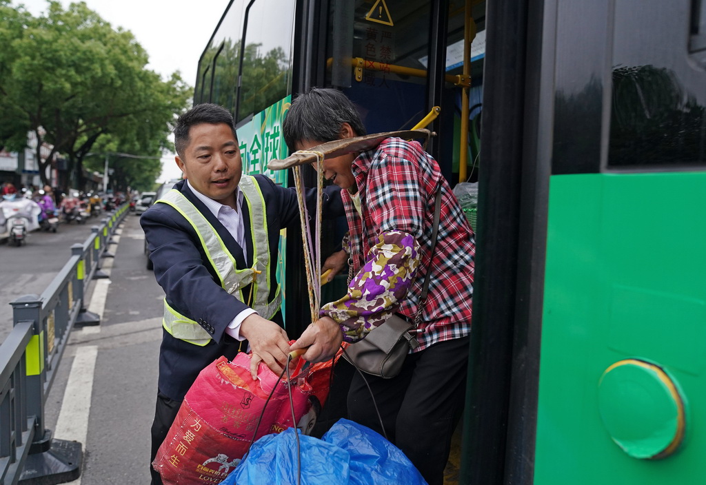在“菜农专线”公交位于南昌市市区的站点，公交安全员协助菜农下车（5月9日摄）。