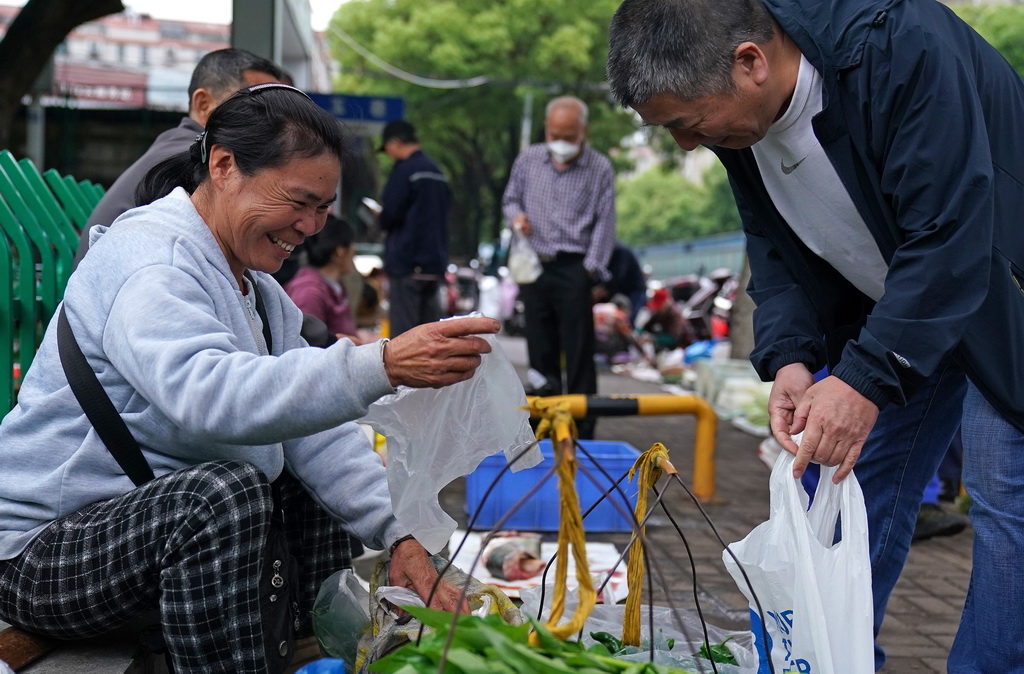 在位于南昌市市区的江农农贸市场，江长花（左）售卖自家种的蔬菜（5月9日摄）。