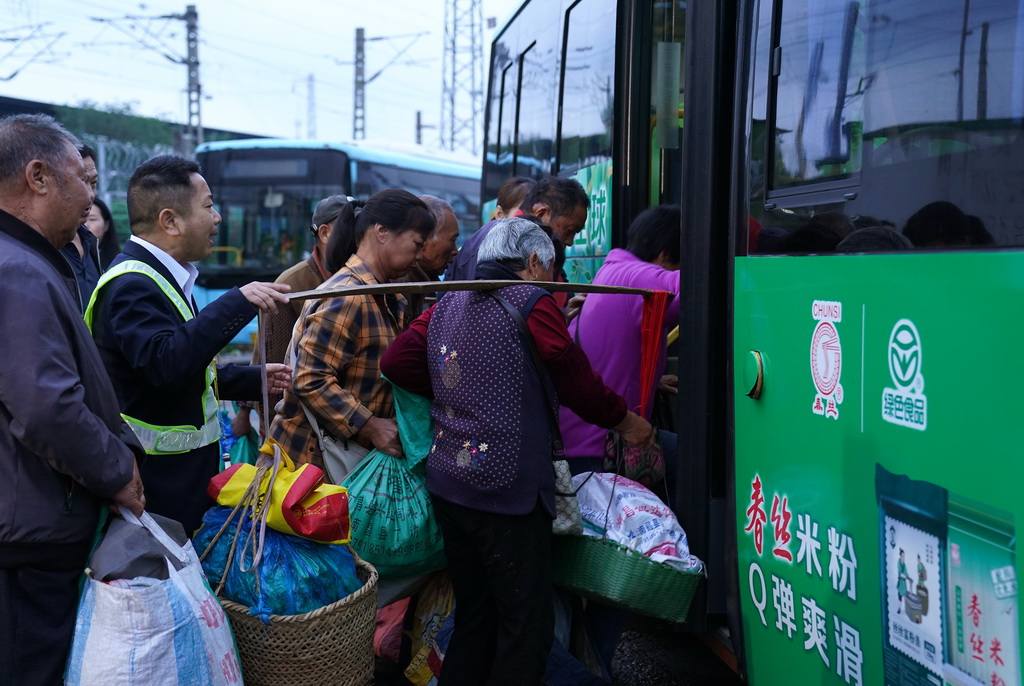 菜农在江西省南昌县向塘镇浃溪村的公交站点上车（5月9日摄）。