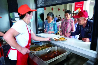 老人们在浙江省衢州市常山县“跨省食堂”窗口排队取餐。